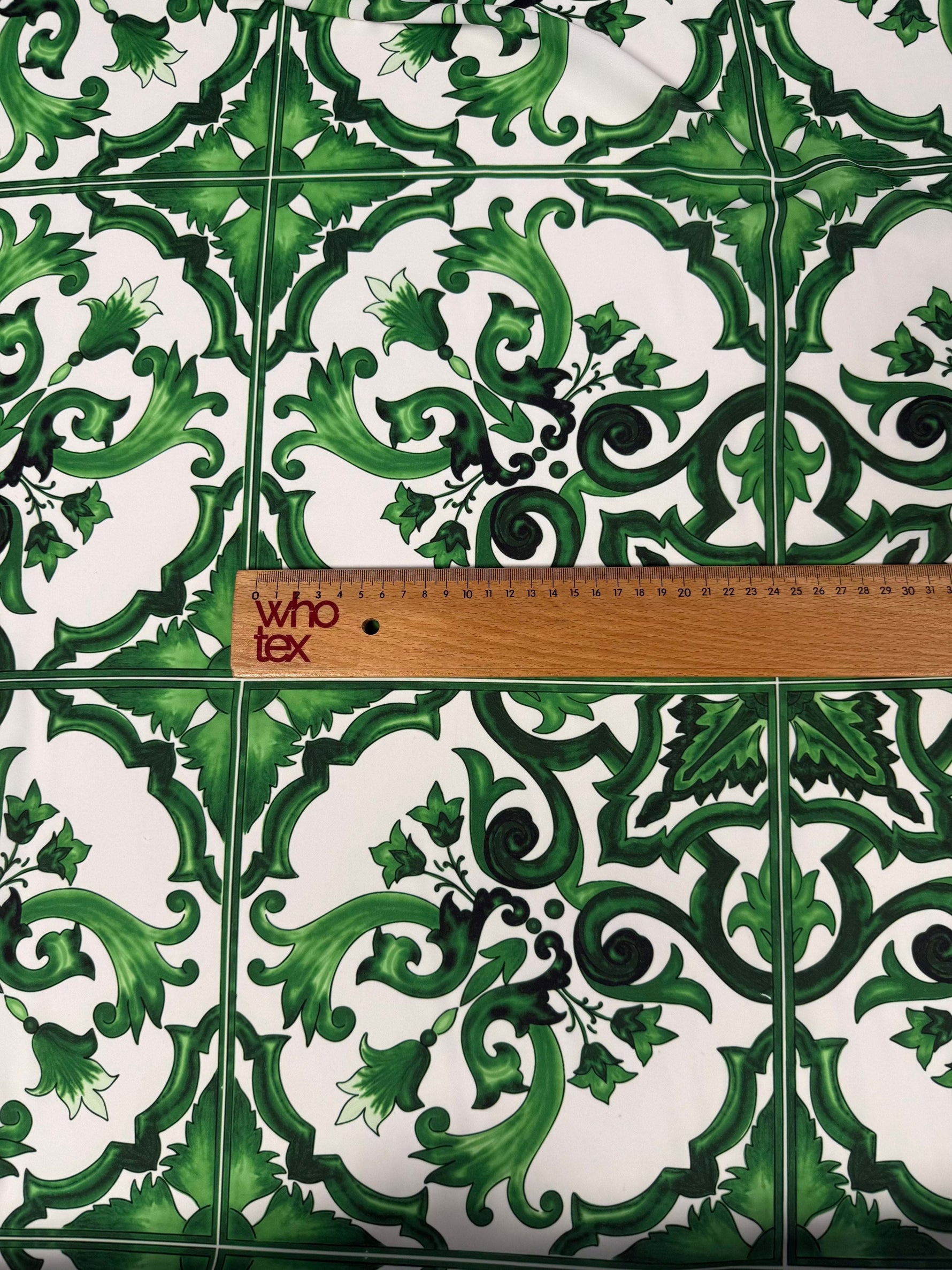 Green Baroque tile pattern fabric with intricate green floral and scroll designs and a measuring ruler for scale