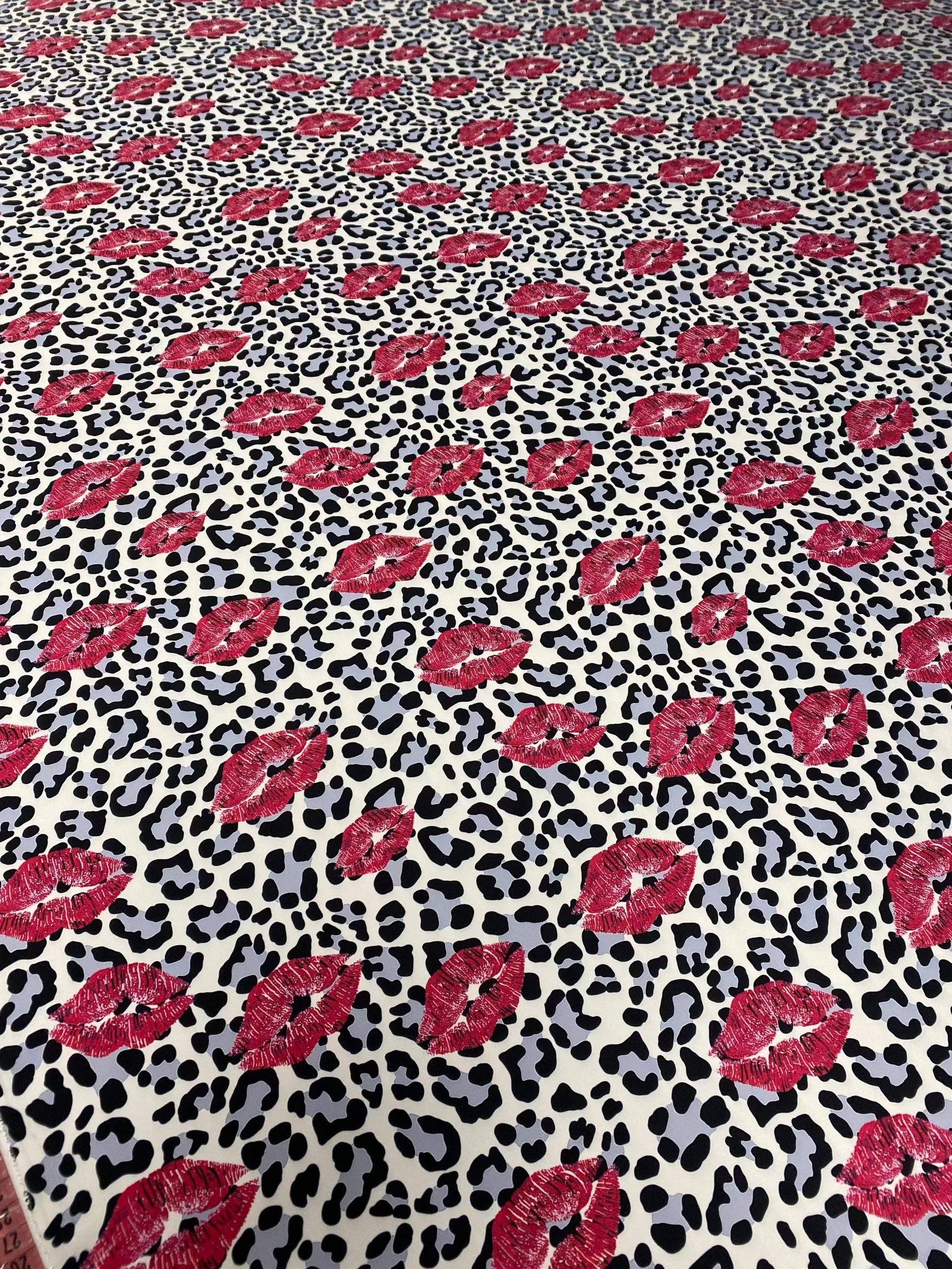 Leopard print fabric with bold black spots and pink lip pattern for upholstery and home decor projects