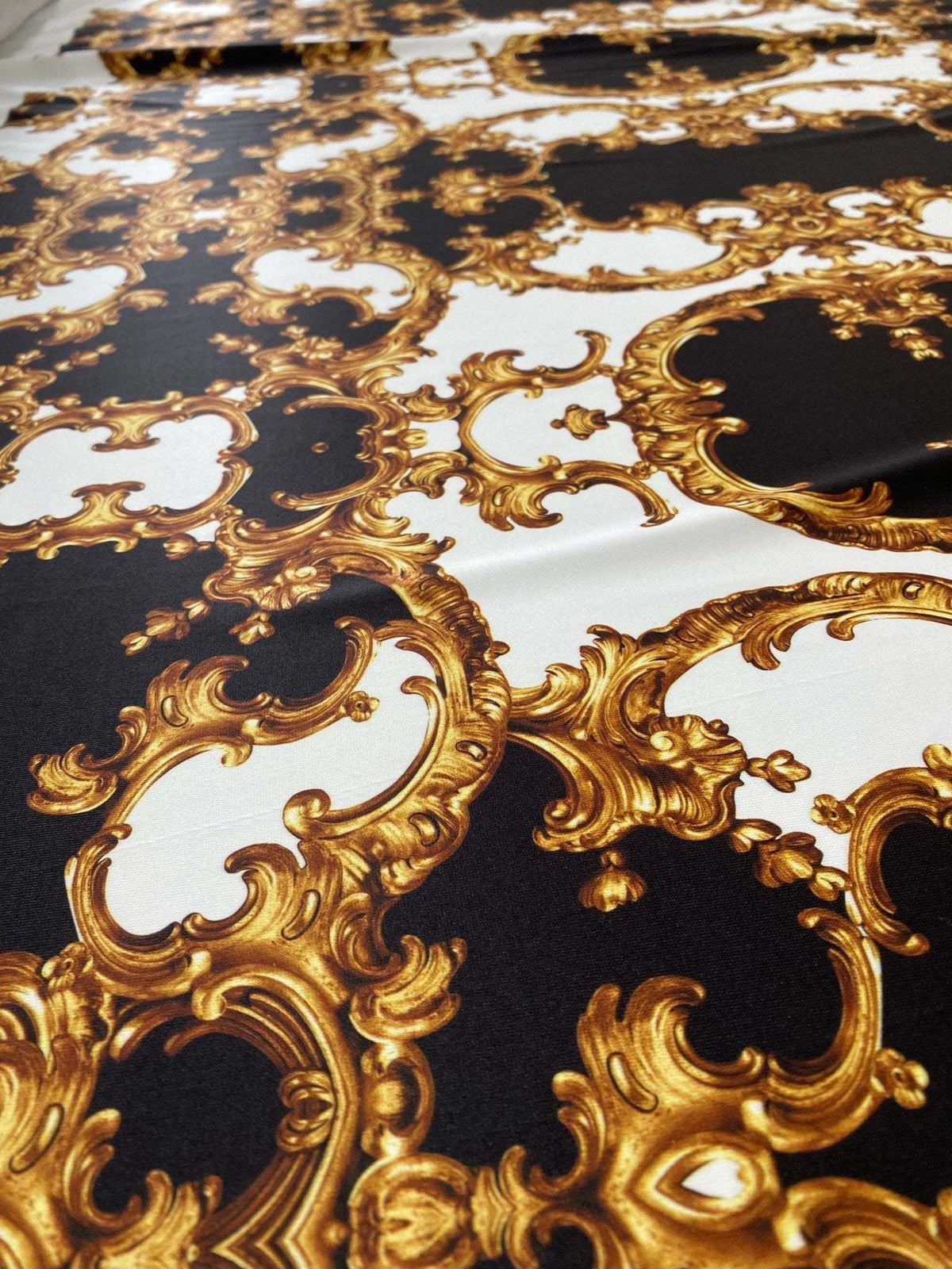 Baroque fabric with intricate black, white, and gold ornate pattern ideal for elegant crafts and sewing projects