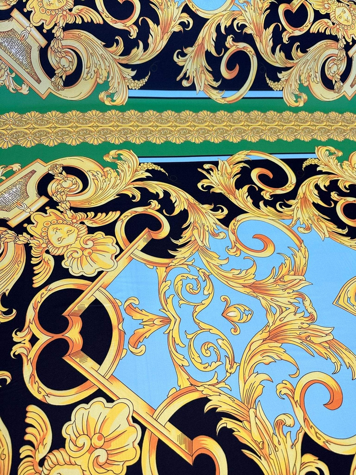 Baroque silky crepe fabric with intricate gold patterns on black, blue, and green background