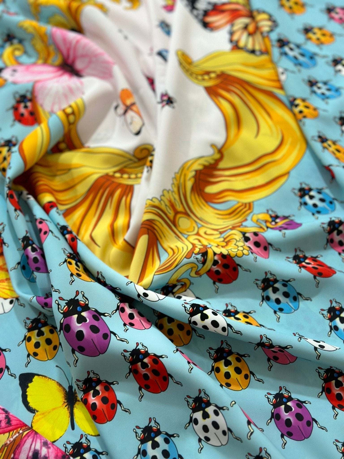 Colorful butterfly and polka dot print fabric with vibrant ladybugs on light blue background