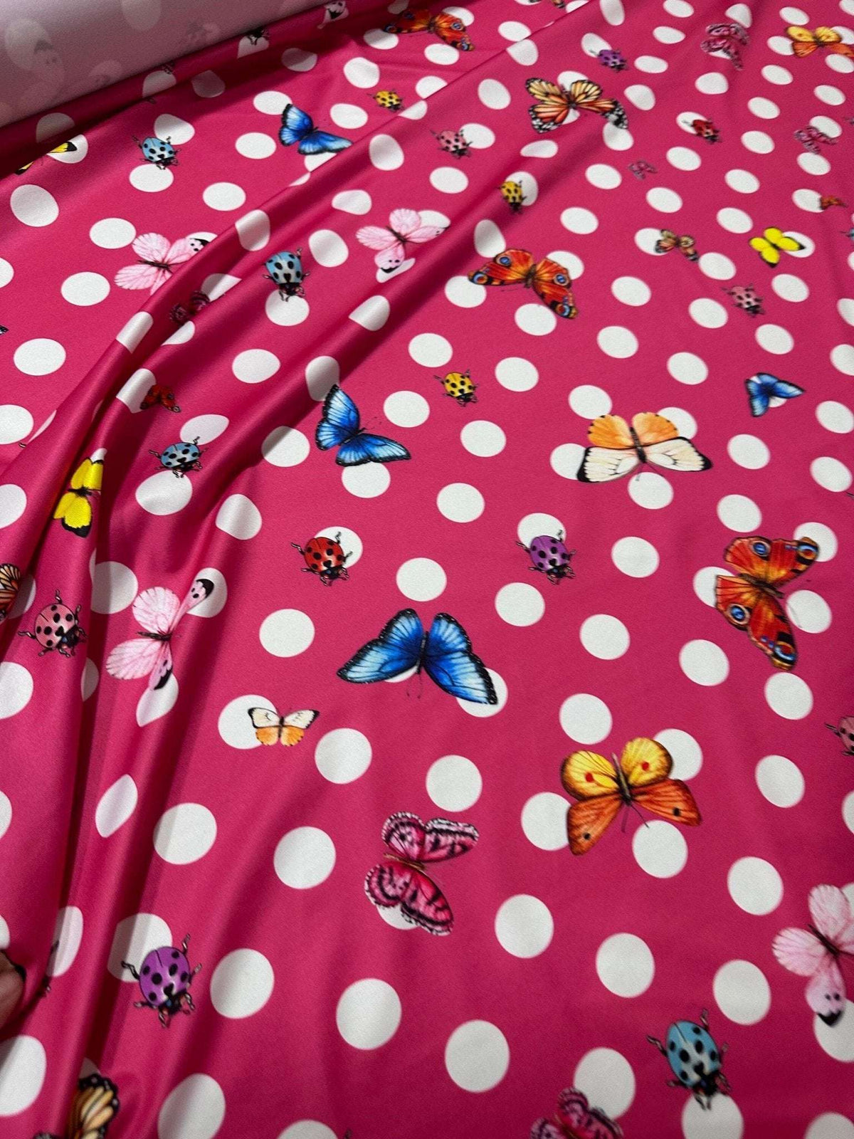 Bright pink butterfly polka dot fabric with colorful butterflies and white polka dots for crafting and sewing projects