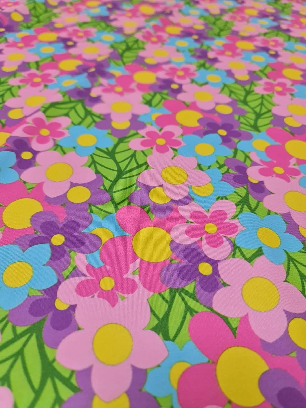 Colorful floral fabric with vibrant pink, purple, blue, and yellow flowers and green leaves pattern
