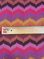 Colorful zigzag chevron pattern knit fabric in green, pink, purple, and yellow tones with ruler for scale