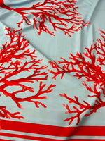 Silky crepe fabric with vibrant red coral pattern on light blue background