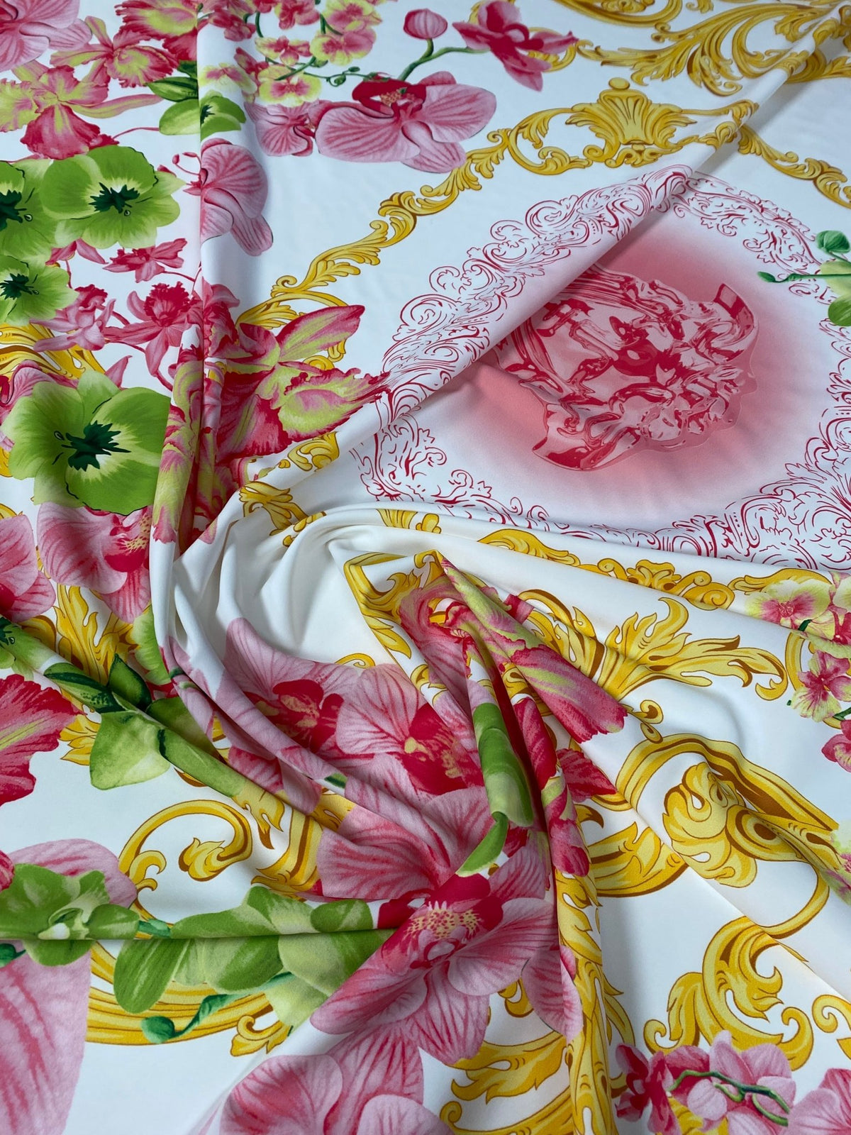 Floral & Baroque Crepe Fabric by the Metre – Pink Green Gold draped on a surface, showcasing vibrant floral and baroque patterns.