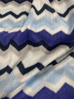 Close-up of blue, purple, beige geometric zigzag patterned woven fabric with textured knit mesh design