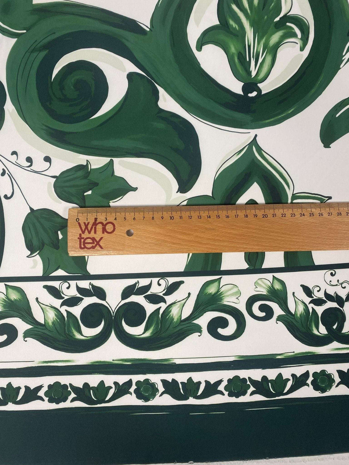 Green Baroque Floral Fabric with intricate green floral and scroll patterns on white background, ruler for scale