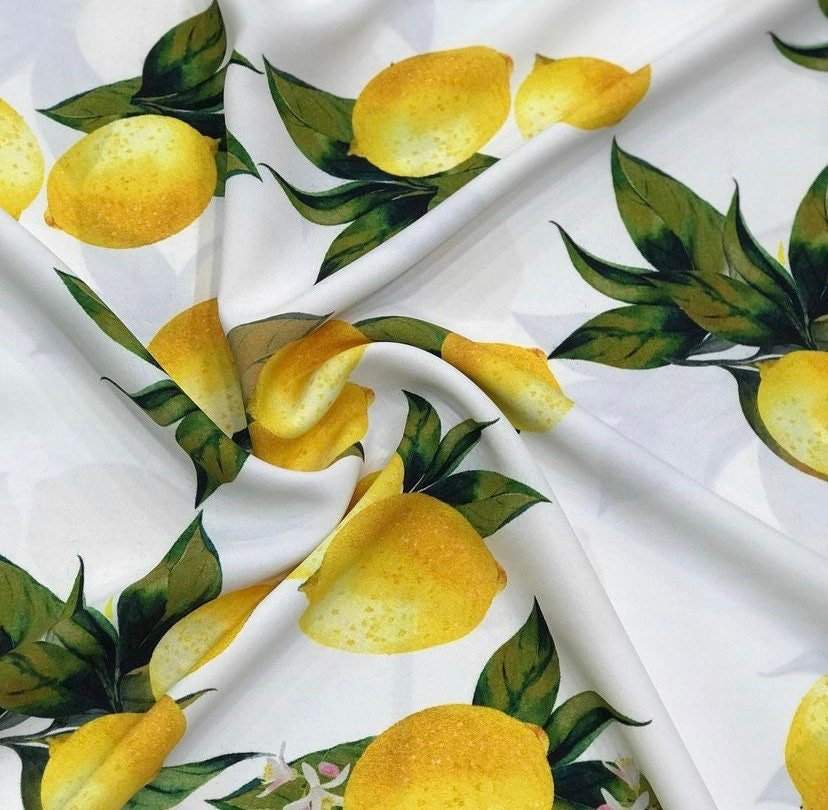 Yellow lemon pattern cotton fabric with green leaves on white background