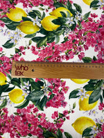 close-up of lemon pink floral fabric with vibrant lemons and pink flowers alongside a wooden ruler showing fabric scale