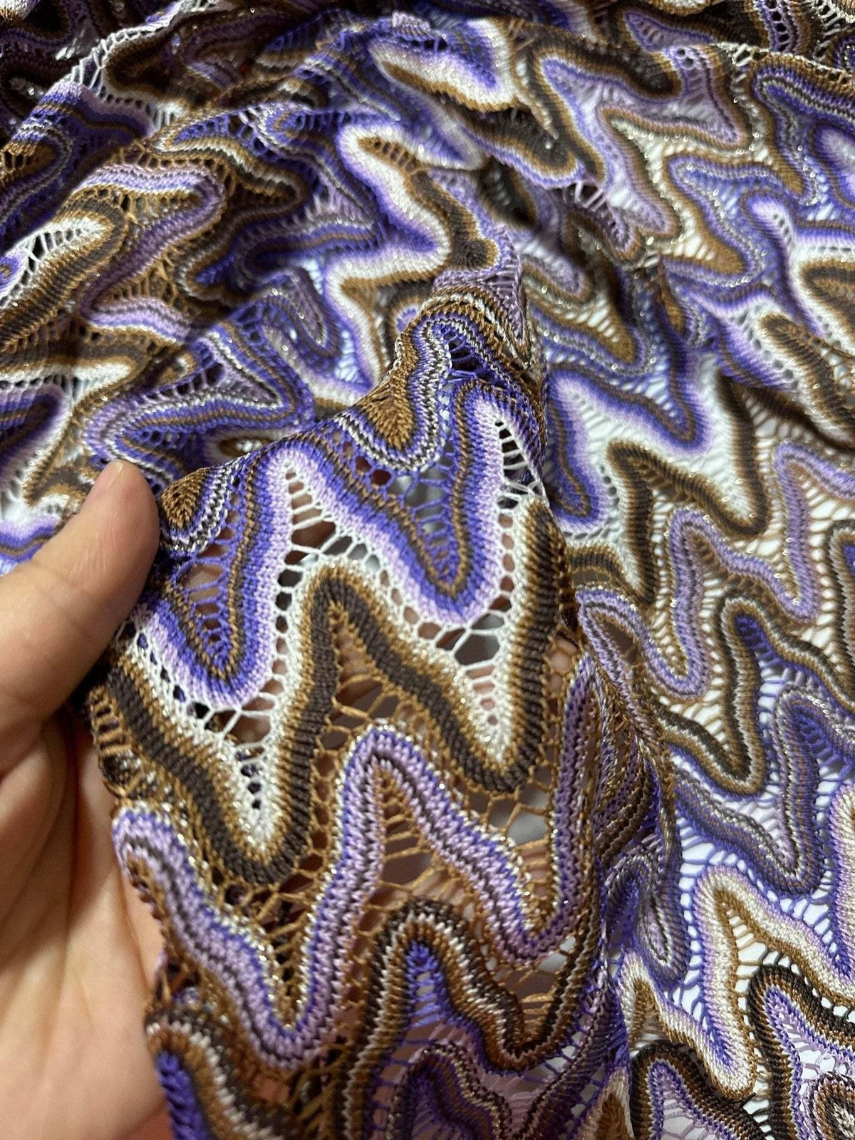 close-up of purple brown zigzag knit jersey mesh fabric with intricate openwork pattern for sewing projects