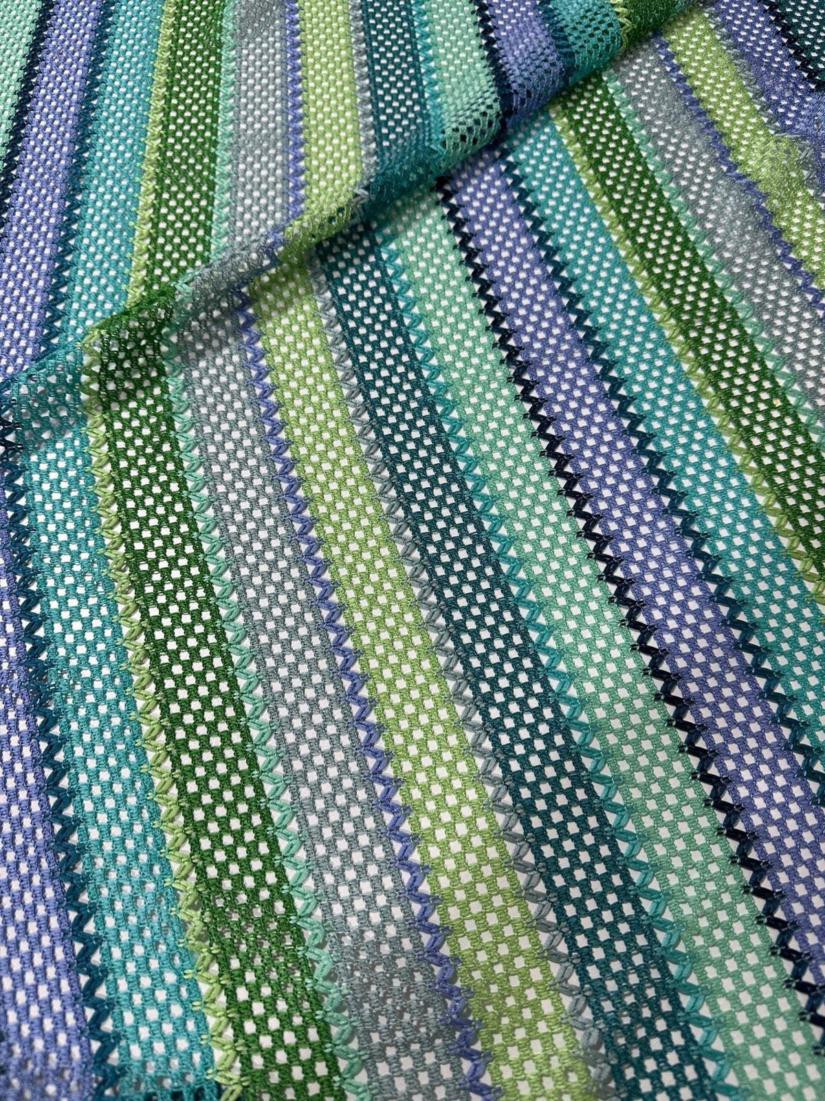 Striped knit mesh fabric in green tones with zigzag pattern for creative sewing projects
