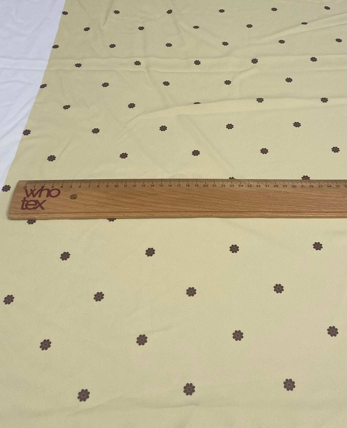 Minimal yellow fabric with small brown floral pattern and wooden ruler on top
