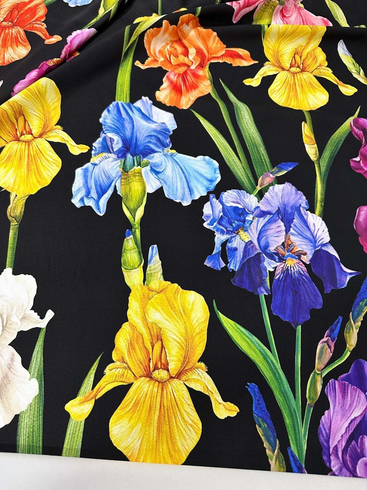 Black floral crepe fabric with vibrant yellow, blue, purple, orange, and white flower patterns.