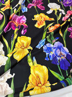 Black floral crepe fabric with vibrant yellow, purple, pink, white, and blue flowers and green leaves