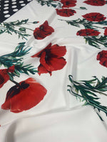 Red poppy floral fabric with green stems and polka dot border on white background