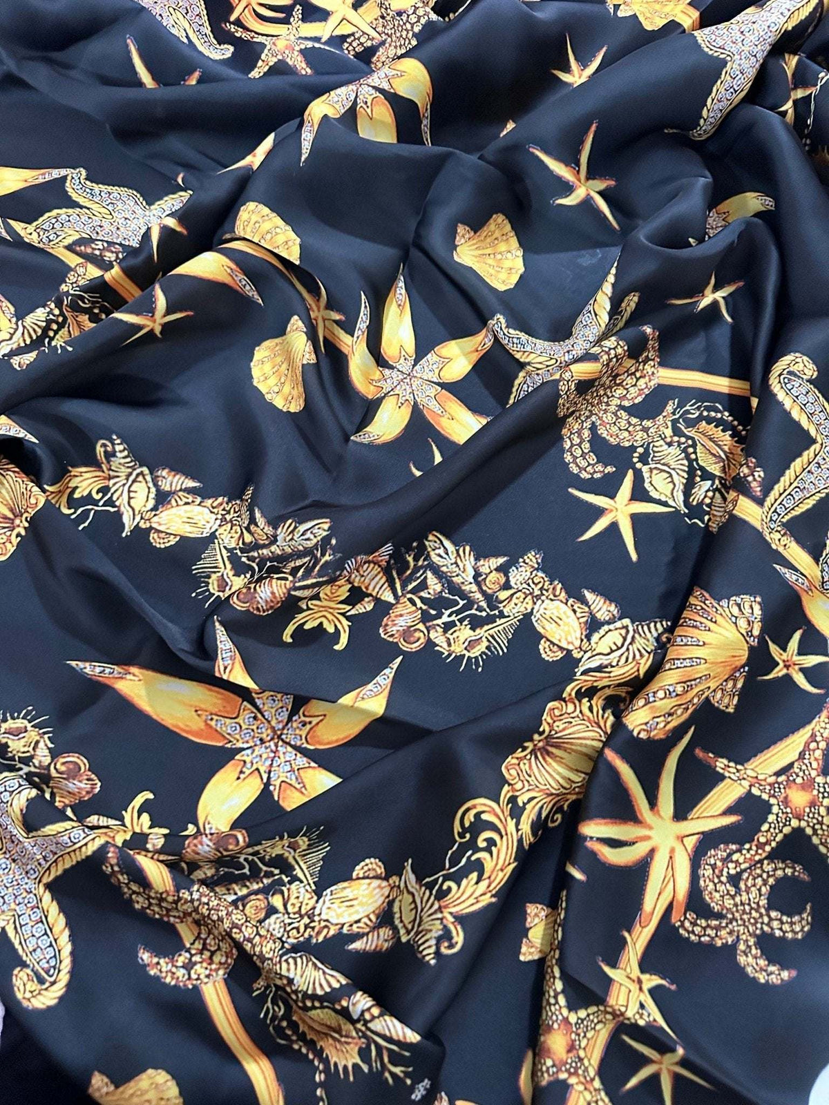 Black luxury fabric with intricate gold sea shell pattern on a deep black background