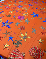 Orange fabric with colorful oyster and sea shell pattern for sewing and crafting projects