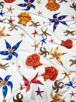 White sea shell fabric with colorful starfish and shell patterns perfect for coastal-themed sewing projects