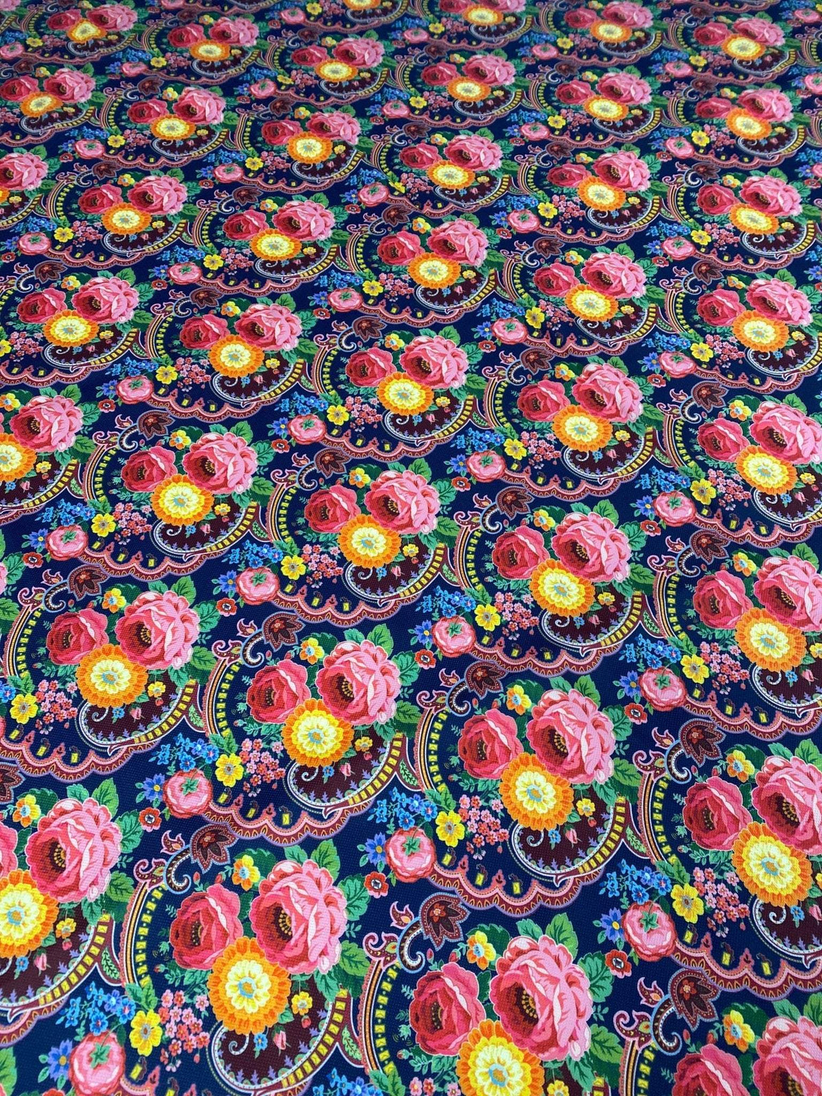 Close-up of vibrant tiny floral design upholstery fabric with pink and yellow flowers on a dark blue background