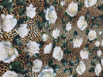 Floral and cheetah pattern fabric with white roses and green leaves on a cheetah print background