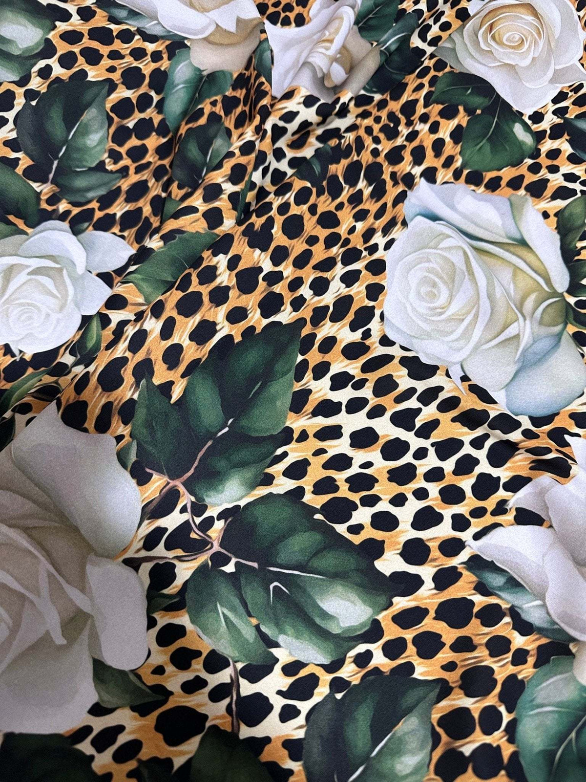 Floral and cheetah pattern fabric with white roses and green leaves on a cheetah print background