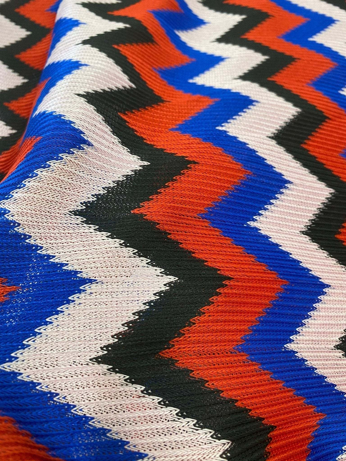 Luxury zigzag knit jersey fabric with blue, red, black, and sugar pink zigzag pattern and soft stretch texture